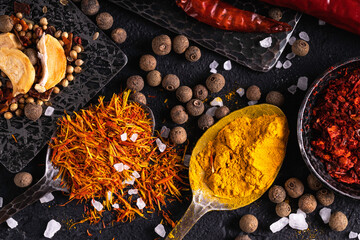 Set of spices for cooking. Various spices in spoons and bowls on the dark background. 