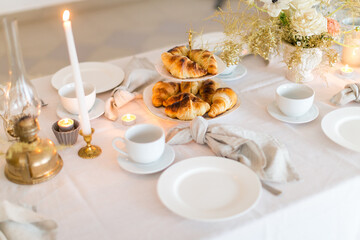 Christmas decoration of the festive table with cakes, glasses and candles