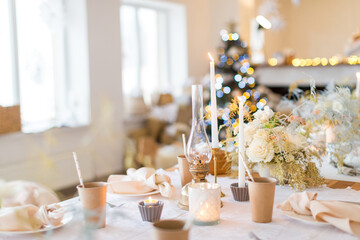 Christmas decoration of the festive table with cakes, glasses and candles
