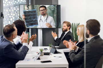 Front view of five multiracial business people, healthcare experts, discussing cost efficiency of treatment plan of patient while having video conference meeting with their Caucasian colleague