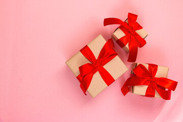 Gold heart shaped balloon and gift box with a red bow on a pink background. Valentine's day concept. Copy space for text.