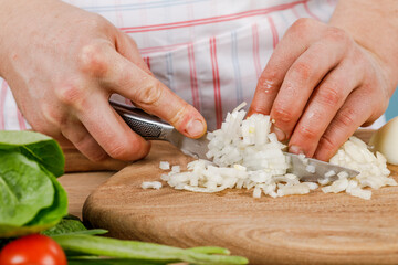 man cuts a white onion with a knife. The concept of cooking