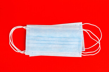 Medical mask, a medical protective mask isolated on a red background. A disposable surgical face mask covers the mouth and nose. Health care coronavirus medical quarantine, hygiene concept