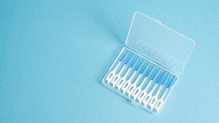 Top vie of interdental brush in portable case on blue background. Small brush for teeth. Home dental hygiene