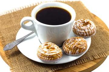 Morning snack. Cup of black hot coffee with delicious choux pastry. Kitchen wooden board with napkin.