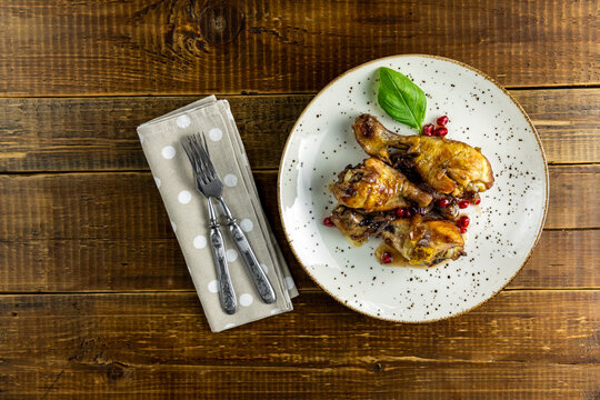 Baked chicken drumstick with apple jam in a light dish on rustic wooden table surface, top view, copy space.