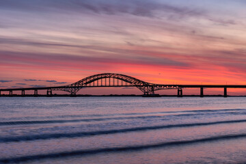 Vibrant sunset colors over a steel tied arch bridge. Fire Island Inlet Bridge, Captree State Park New York