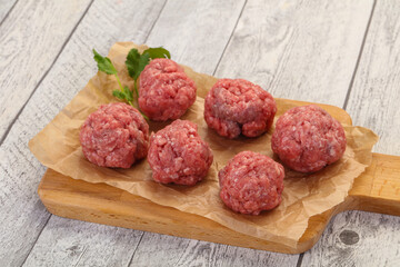 Raw meatball over wooden background