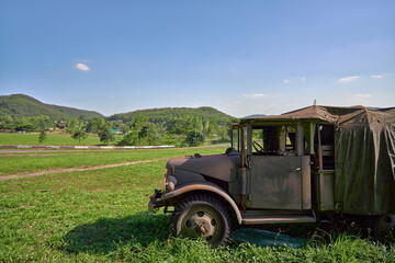 A military vehicle on a green meadow Behind it is a mountain and a clear blue sky with copy space.