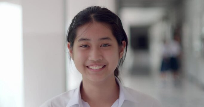 A cute Asian female student teen girl in white uniform is laughing fun.
