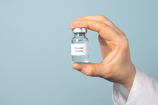 A doctor or laboratory technician keeps the Prevenar vaccine on a blue background. Vaccination against pneumocococy, prevention of pneumonia in infants