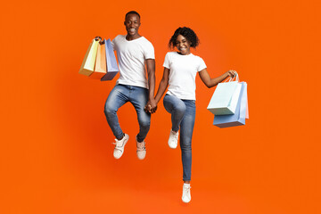 Happy black man and woman with purchases jumping up