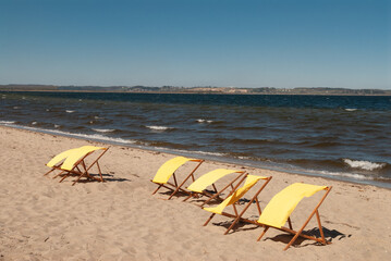 
Yellow sun loungers on an empty beach on a windy sunny summer day