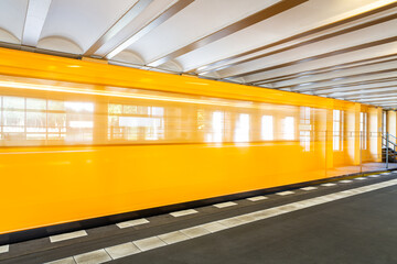 Yellow subway train in motion going throw a station
