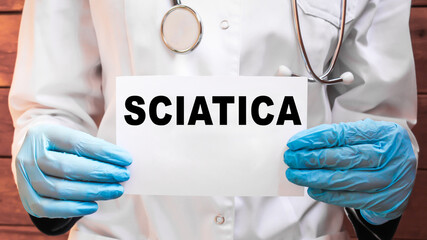 The doctor's blue - gloved hands show the word SCIATICA - . a gloved hand on a white background. Medical concept. the medicine