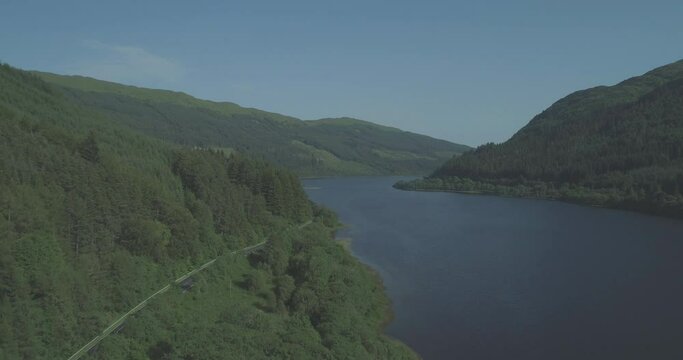 Car with kayaks travelling along mountain road on a road trip beside Loch Lubnaig in the Trossachs, Scotland and evergreen forest