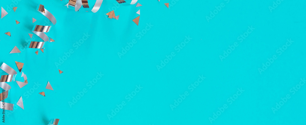 Wall mural close up on group of silver color of rolling ribbon and confetti on teal background with copy space 