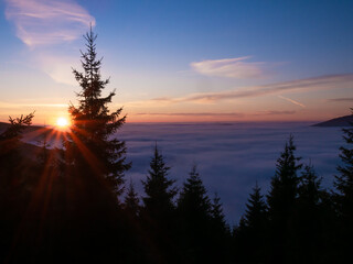 View from mountain range to the valley above fog and clouds at sunset