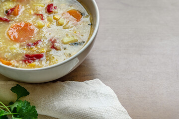 hearty vegetarian vegetable soup with bulgur and corn in a ceramic bowl