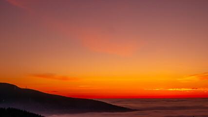 Fototapeta na wymiar View from mountain range to the valley above fog and clouds at sunset