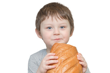 Portrait of a blue-eyed little boy holding a large loaf of bread in his hands. Will eat it. Horizontal photo, isolated on white background, looks at the camera