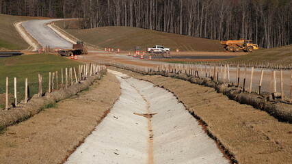 New concrete drainage channel with survey stakes along the side of a new road bed for a highway project
