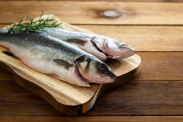 Seabass fish isolated on wooden background, top view.