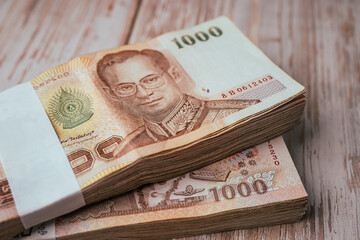 Stack of Thai baht banknotes on wooden background, business saving finance investment concept.