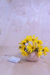 yellow flowers in a vase and a gift box on a wooden background