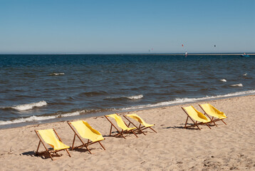 Yellow sun loungers on an empty beach on a windy sunny summer day