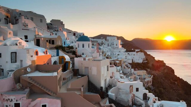 Aerial shot flying over Oia village and revealing the cliffs of Santorini at sunrise