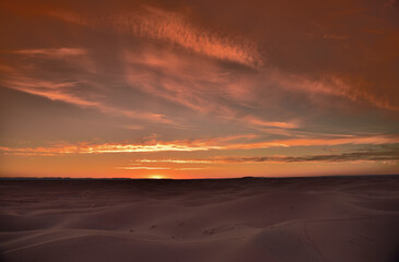 Fototapeta na wymiar Roter Sonnenuntergang in der Wüste mit einem bewölkten Himmel