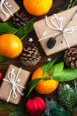 Christmas new year background with tangerines, gift boxes pine cones, winter decorations over wooden background