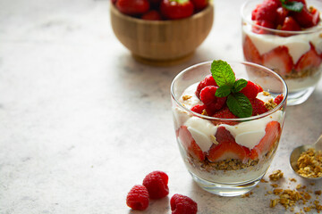 Layered yogurt, granolla and fruits, strawberry ans raspberry. Healthy breakfast copy space.