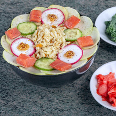 Raw fish, rice and fresh vegetables in bowls on a wooden background. Healthy food concept