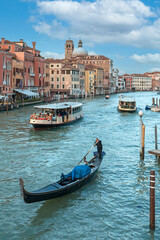 Fototapeta na wymiar gondola and tourist ships sailing along the Grand Canal in Venice against the backdrop of beautiful houses and blue sky