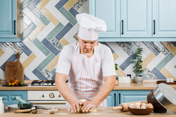 Smiling man kneads dough at home. The concept of baking. Copy space