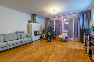 View of room with Сhristmas decoration and view of traditional advent candlestick with four lighted candle  symbolizing fourth advent.