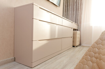 Large, long, light chest of drawers in the bedroom. Beautiful modern bedroom interior