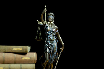 Statue of justice and old Books. Close-up Of Justice Lady Against Black Background