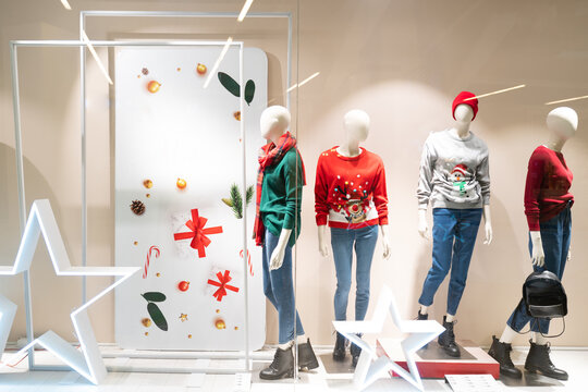 christmas and new year excitement at shopping mall. brands decorated windows for new year. colorful lights ugly Christmas sweaters, mannequins, decoration, green, red and golden yellow. blank area