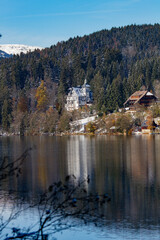 Fototapeta premium Titisee-Neustadt, Germany - 10 30 2012: beautiful white house castle on the coast of Titisee, european village in beautiful winter cold day. House reflected in the lake