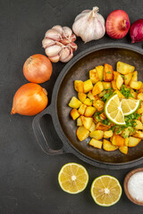 top view tasty fried potatoes inside pan with onions and garlics around on dark background cuisine meal food calorie pepper