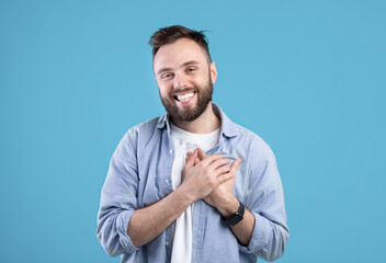 Cordial millennial guy holding his hand on chest, expressing gratitude and positive emotions on...