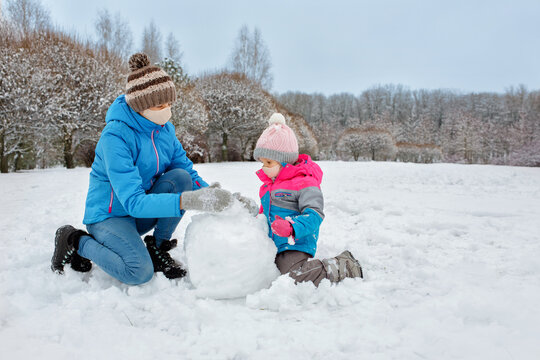 Mom And Daughter Play In The Fresh Air In Med Masks Making A Snowman