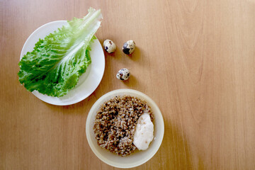 On a white plate, lettuce and sawn eggs, a plate of buckwheat. Place for text.