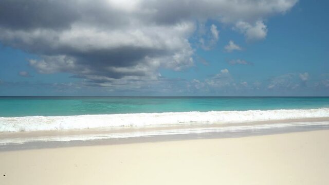 Exotic beach by the ocean with rolling waves on the sandy shore and blue sky