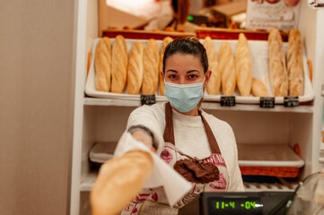 Bakery owner holding bread wearing surgical mask. New normal concept.