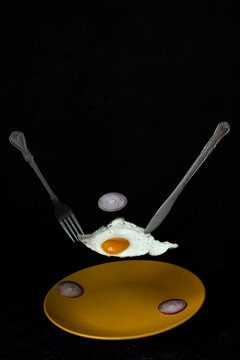 Levitating Scrambled Egg On A Yellow Plate. Black Background