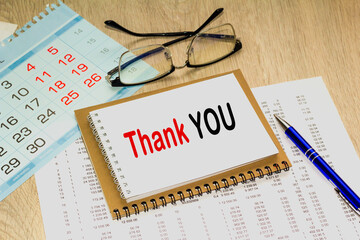 THANK YOU. blank notebook with markers pen beside. The notebook is on paper with text . Colored pencils and eyeglasses. Concept photo for BUSINESS, FINANCE, MARKETING
